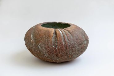 Round ceramic pot with textured brown surface and green interior.