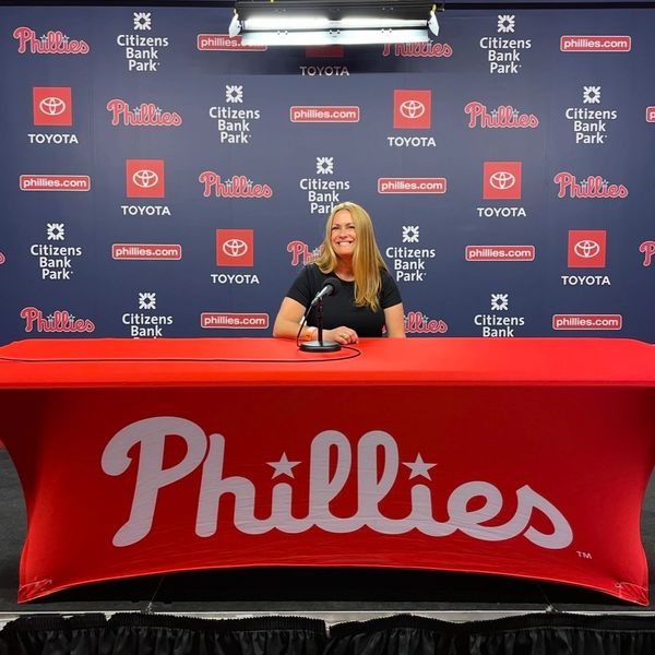A woman sitting at a Phillies press conference table with microphone.