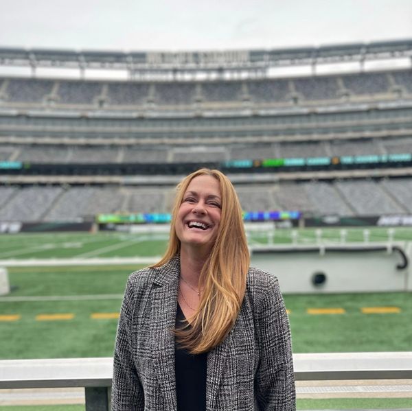 A woman smiling in a stadium with empty seats.