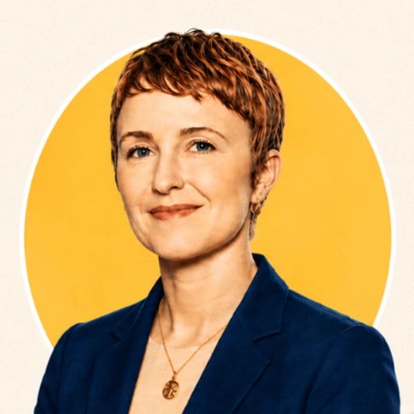 Confident woman with short hair in a blue blazer against a yellow background.