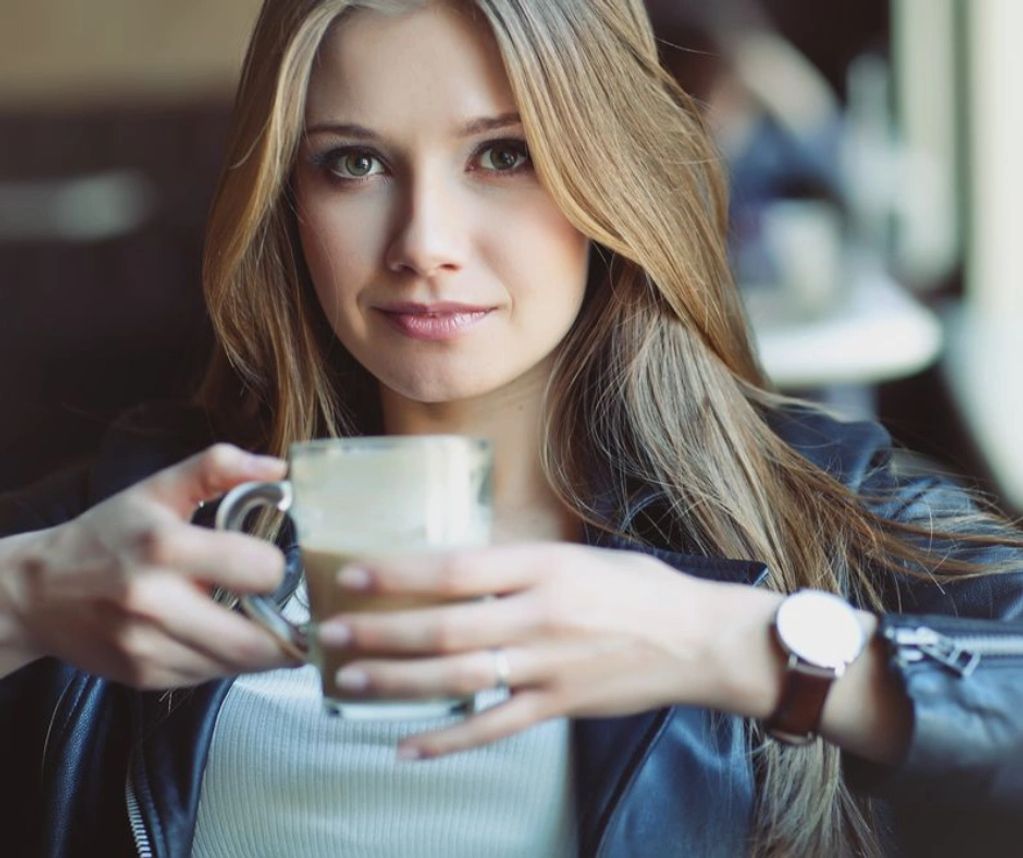 dark blonde young female, wearing leather jacket, drinking a latte