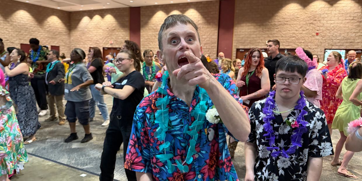 People dancing and having fun at an indoor Hawaiian-themed party.