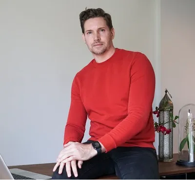 The image is a photo of Mark Houston, LCSW sitting with his hands placed on his right knee.