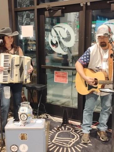 Two musicians performing indoors with guitar and accordion.