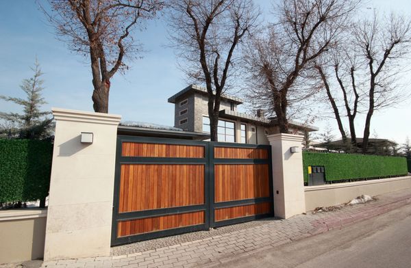 Modern house with wooden gate and leafless trees under clear sky.