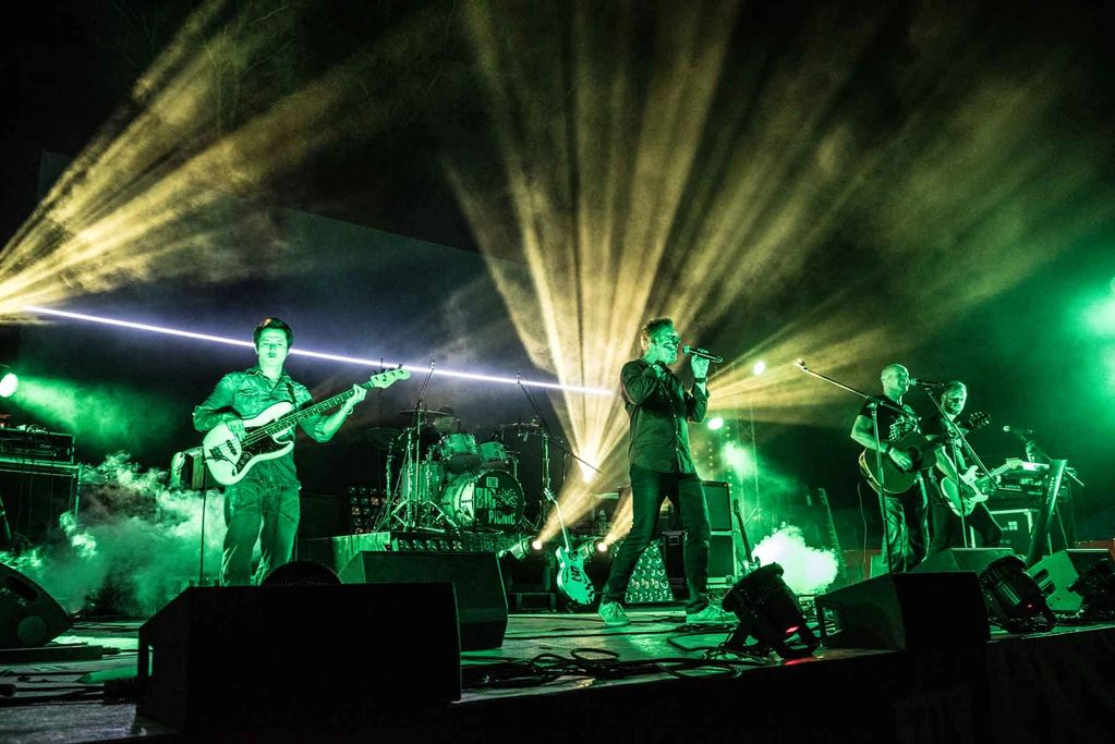 Band performing live with dramatic green and yellow lights.