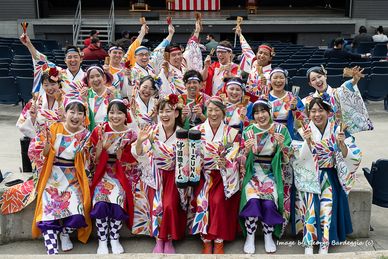 Group of people in colorful traditional Japanese attire smiling and posing together.