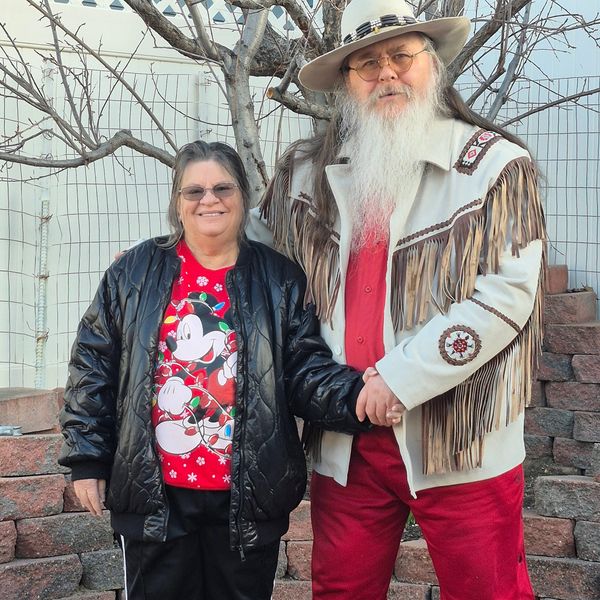 Couple holding hands outdoors, dressed in festive and western attire.