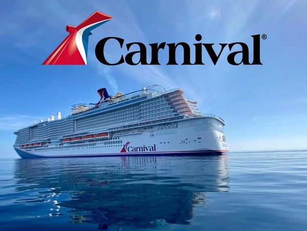 Carnival cruise ship sailing on calm blue waters under a clear sky.