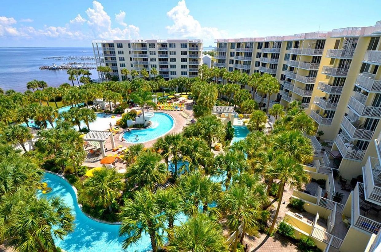 A tropical resort with pools and palm trees by the ocean.