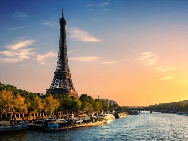 Eiffel Tower at sunset with the Seine River flowing beside it.