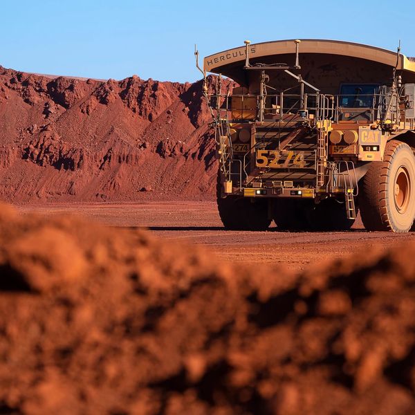 Large mining truck in a red dirt quarry under clear blue sky.