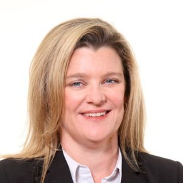 Professional portrait of a smiling woman with blonde hair in business attire.
