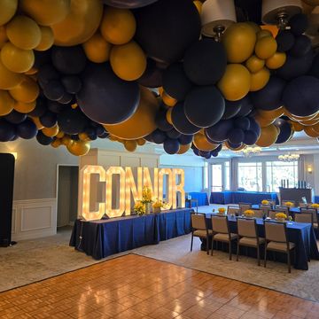 Decorative balloon ceiling with illuminated 'CONNOR' sign at event.