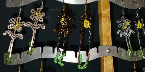 Handcrafted wire and bead earrings displayed on a rack.