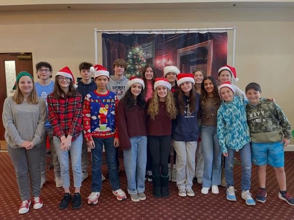 Group of teenagers wearing Santa hats posing indoors.