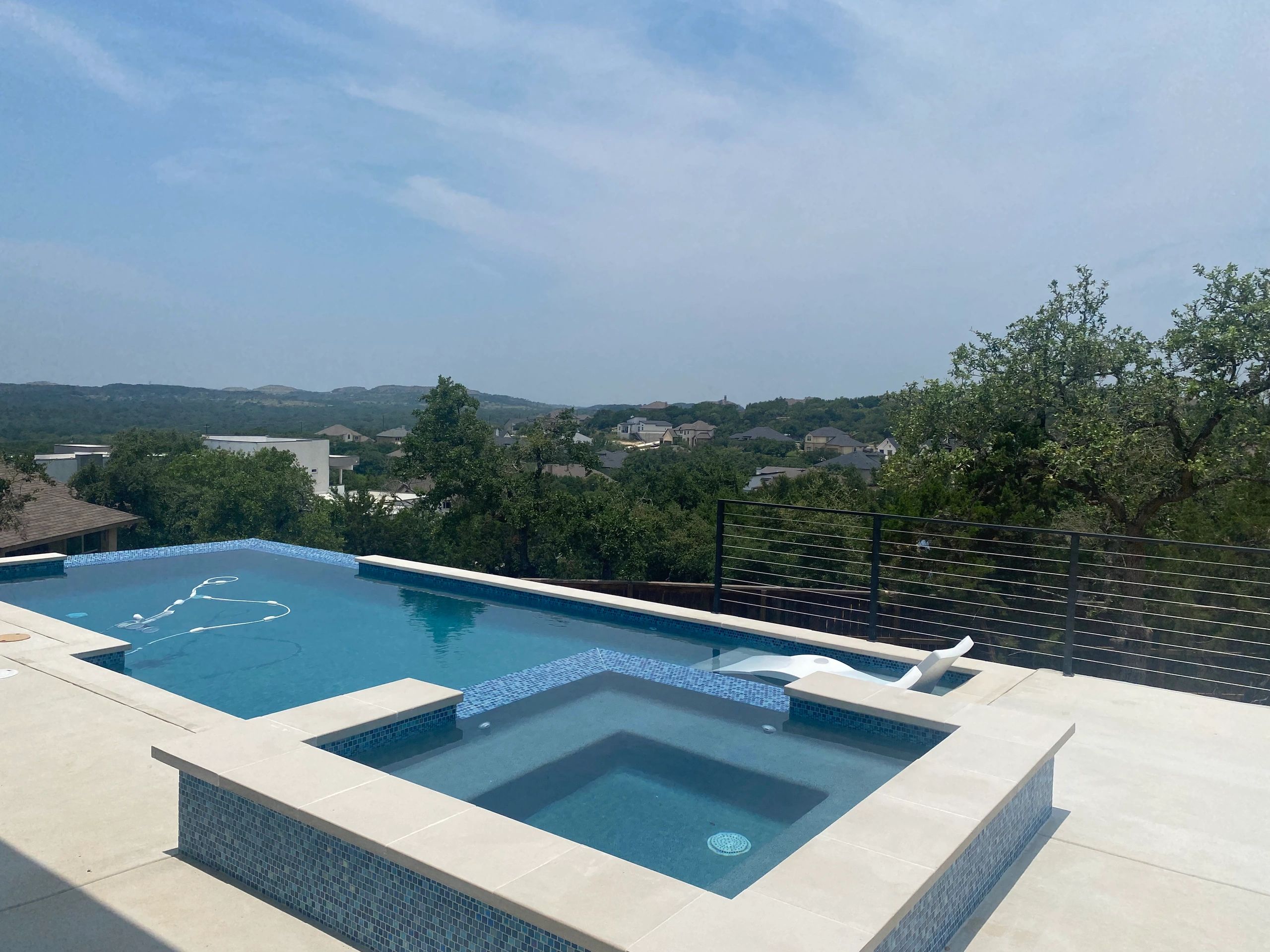 Modern backyard pool with clear blue water and scenic hill view.
