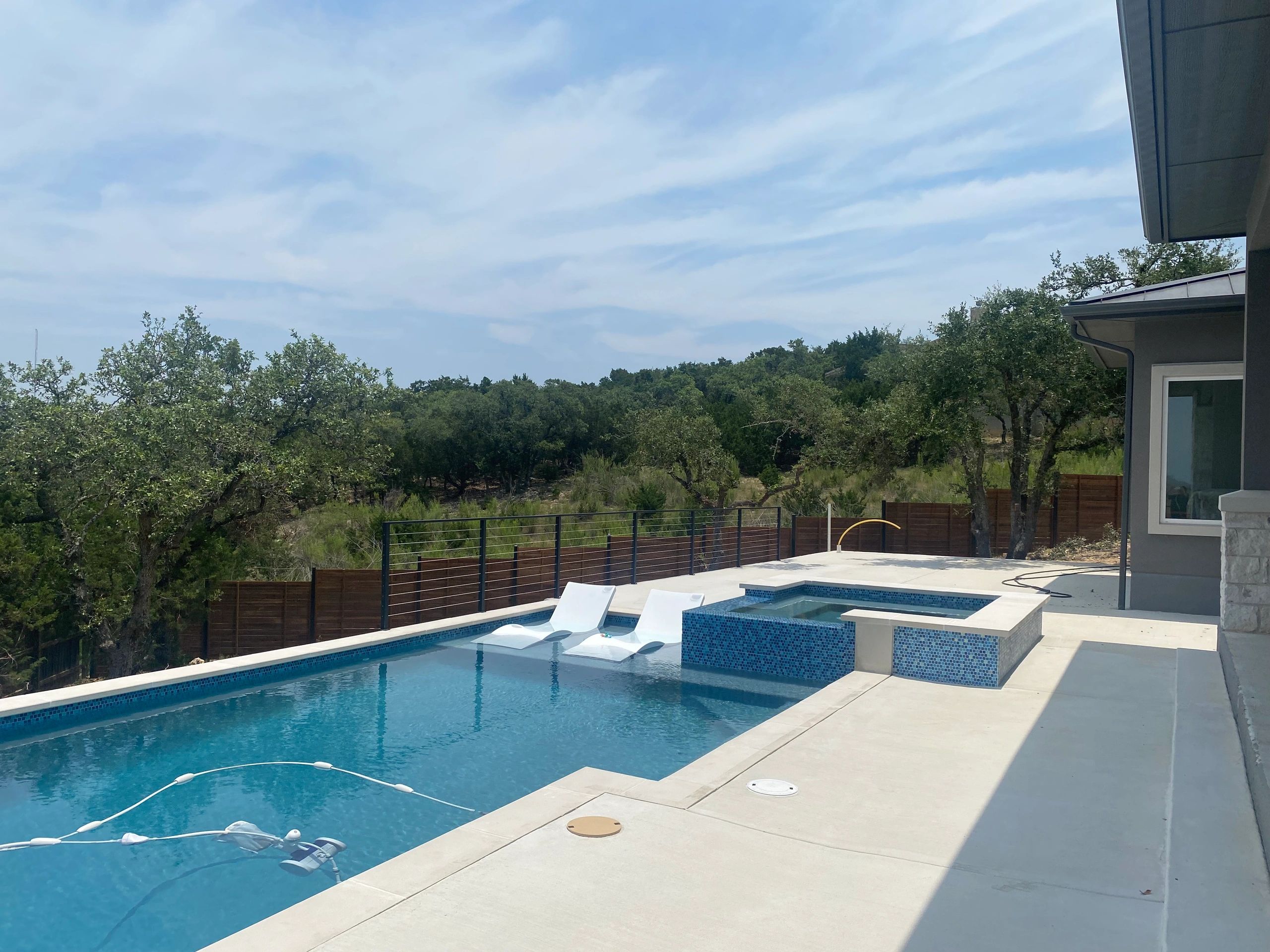 Modern backyard pool with lounge seats and spa.