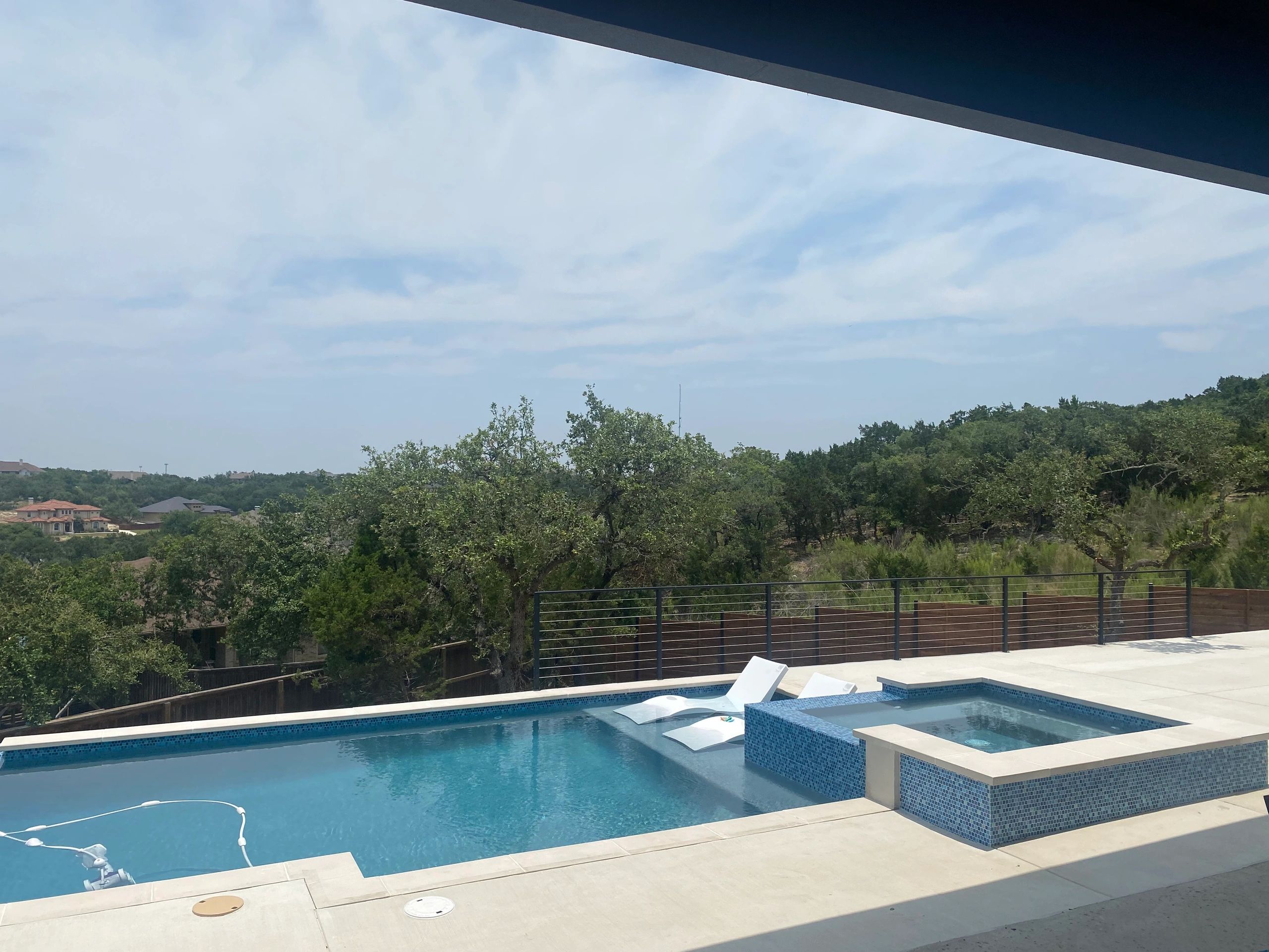 Modern outdoor pool with blue tiles and surrounding greenery.