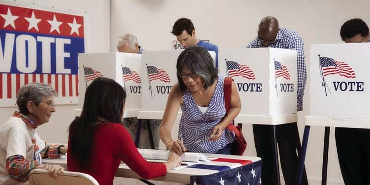 People casting votes at a polling station with patriotic decorations.