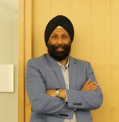 Man in a blue blazer and black turban with arms crossed.