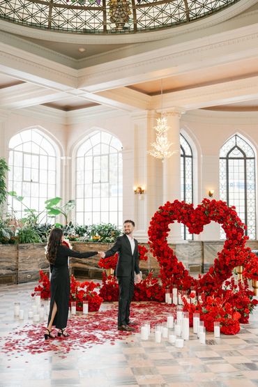 Man and woman holding hands near heart-shaped red rose heart at Casa Loma