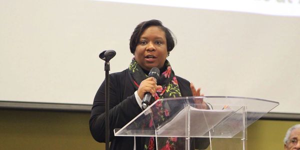Woman speaking at a podium with a microphone.