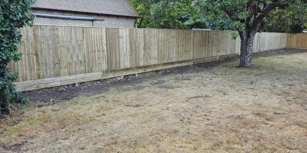 New wooden fence along a backyard with dry grass.