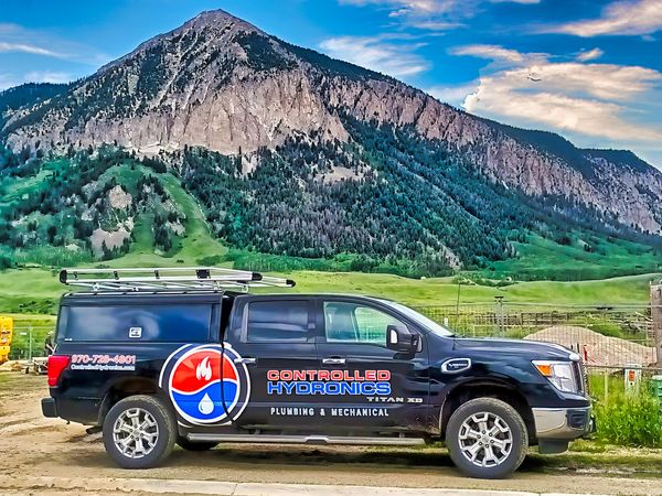 Controlled Hydronics plumbing truck parked with mountain backdrop.