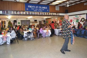 A man speaks at a festive Knights of Columbus gathering with seated guests.
