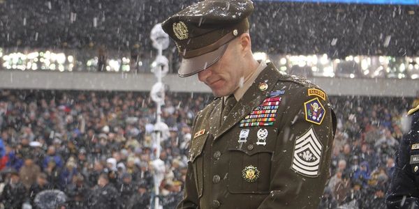 US Army Soldier standing in dress uniform during Army / Navy game.