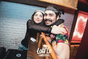 Two friends smiling and hugging inside Lola Lo Cambridge club.