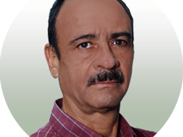 Portrait of a middle-aged man with a mustache wearing a red checkered shirt.