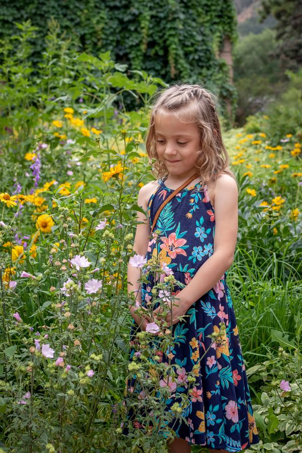 Child portrait, young girl in flower dress standing in flower garden