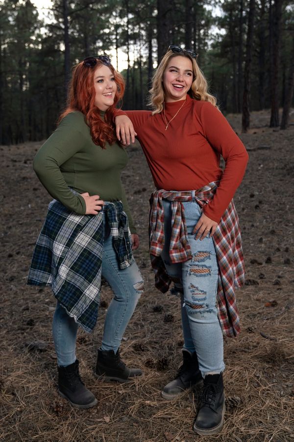 Portrait of two smiling teen girls in trendy clothing wooded background