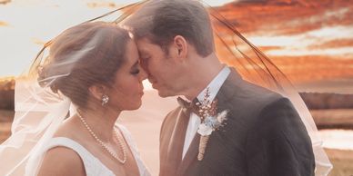 Bride and groom share an intimate moment under the veil at sunset.