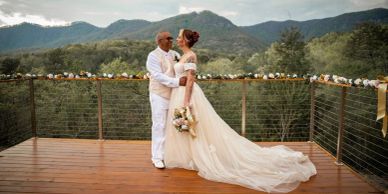 Newlyweds embrace on a scenic mountain deck.