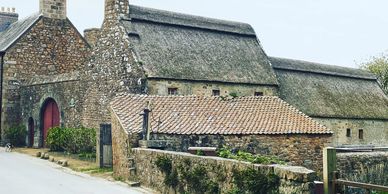 Stone houses with thatched and tiled roofs along a rural road.