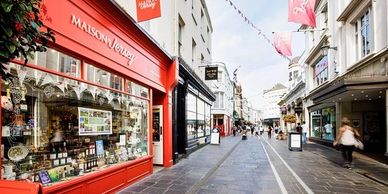 A vibrant street scene with a red storefront and pedestrians walking.