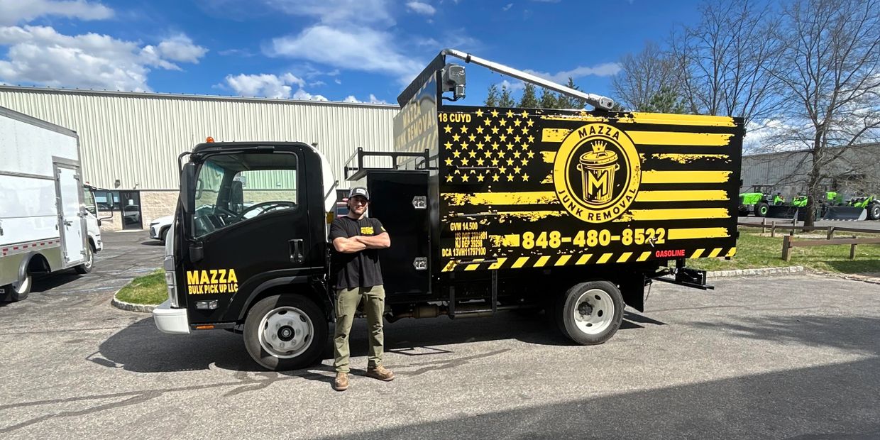 A man stands confidently by a black and yellow Mazza Junk Removal truck.