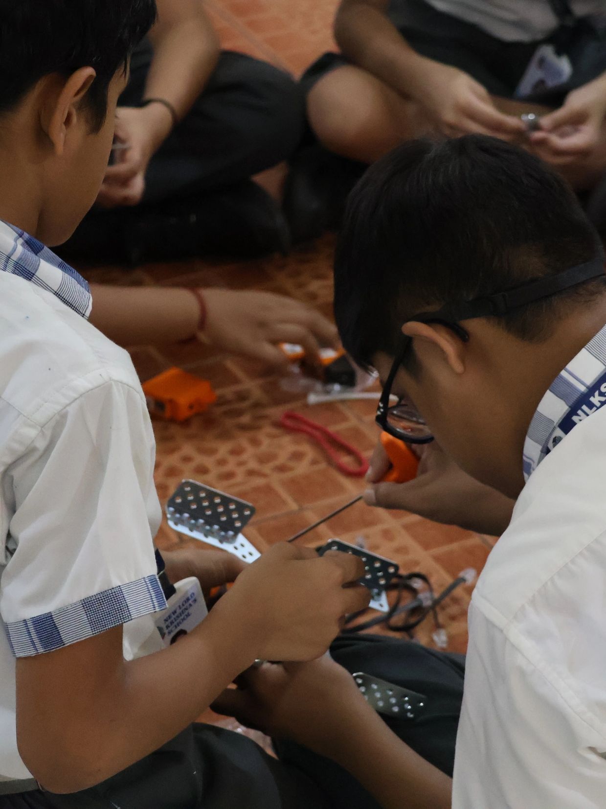 Students assembling a mechanical project on the floor.