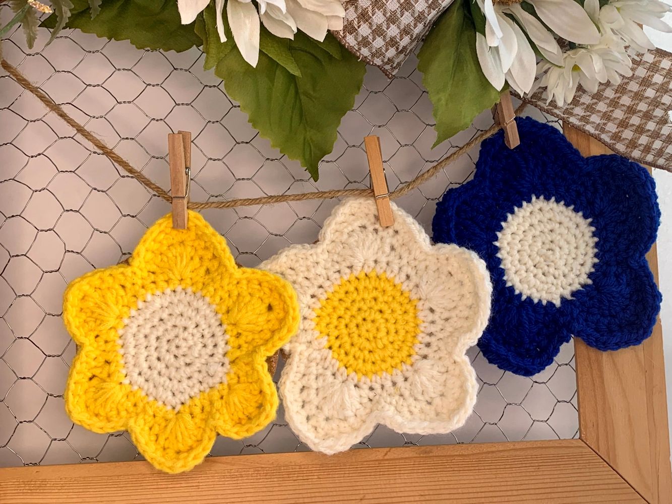Three yellow, white and blue handcrafted crochet coasters.