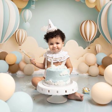 Niño festejando su primer cumpleaños con pastel y globos.