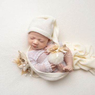 Bebé recién nacido durmiendo con gorro y decoración suave.