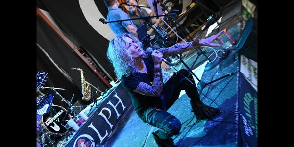 Energetic rock singer with curly hair passionately performing on stage.