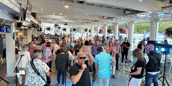 A lively band performs in front of an engaged indoor crowd at a bright venue.