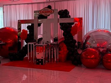 Casino-themed party setup with balloons and a red carpet.