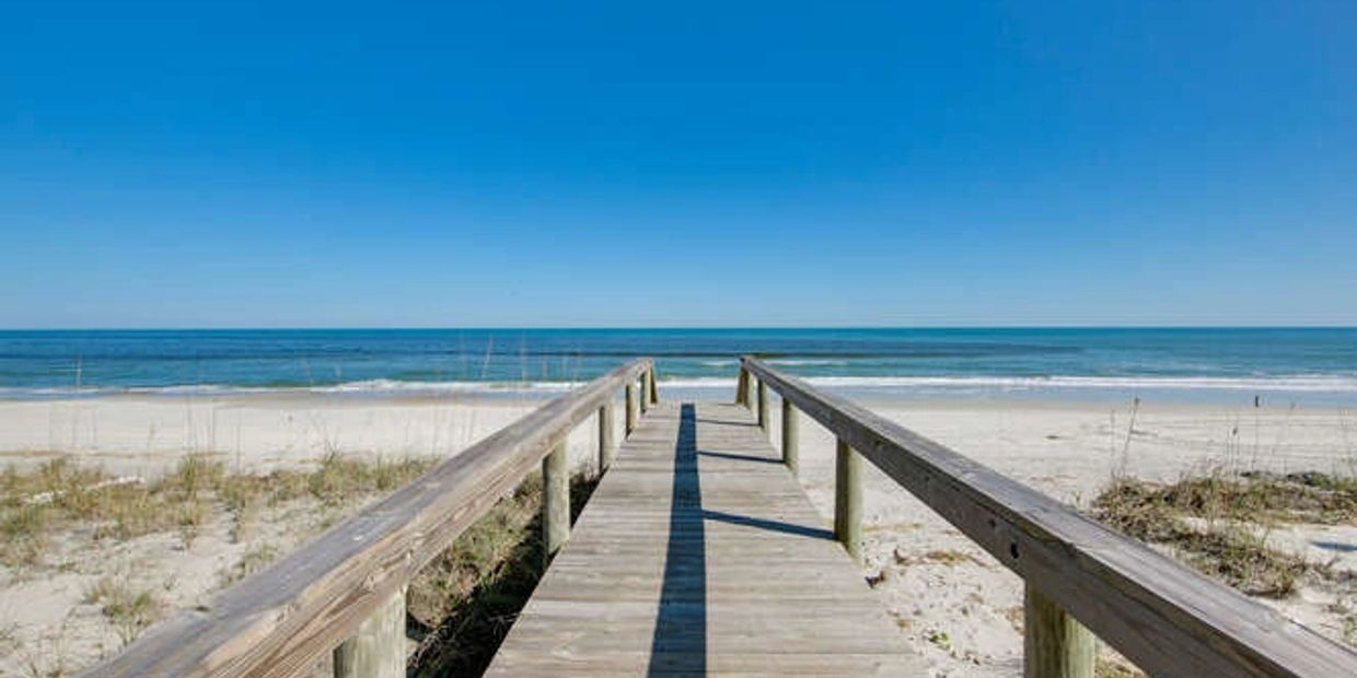 Beautiful boardwalk leading to a pristine beach on a perfectly clear day.