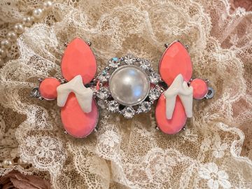 Elegant pearl and coral brooch on lace.
