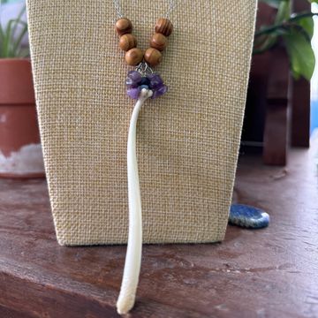 Handmade necklace with wooden beads and a long white pendant.